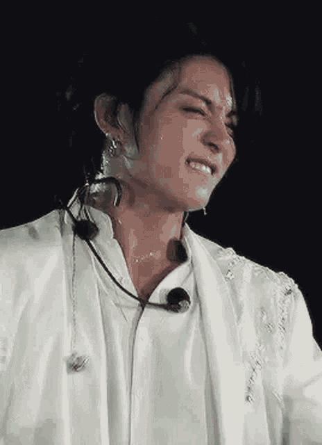 a close up of a person wearing a white jacket and a microphone on a stage .