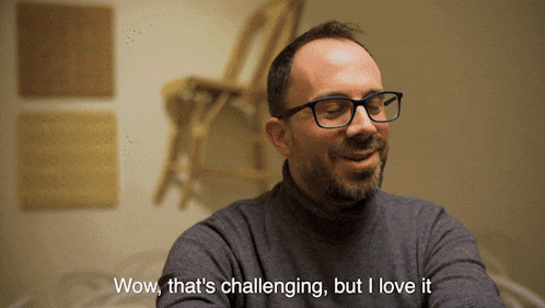 a man wearing glasses and a turtleneck sweater says wow that 's challenging but i love it