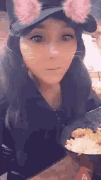 a woman wearing a cat ear hat is eating a bowl of food .