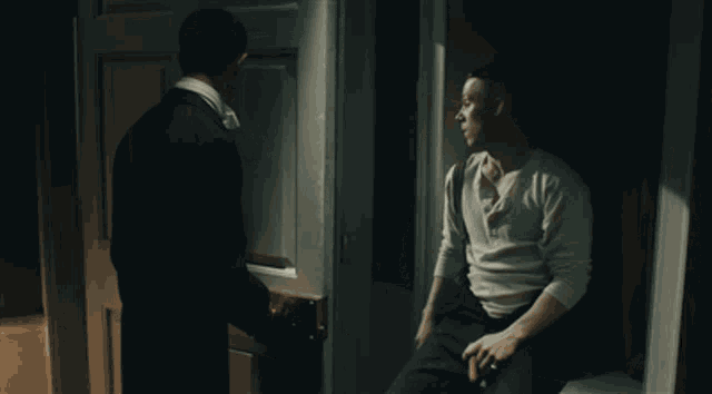 a man in a white shirt is standing next to a man in a black suit
