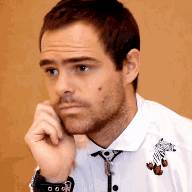 a man wearing a white shirt with a zebra and butterflies embroidered on it