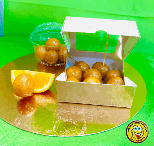 a box of orange balls sits on a gold plate