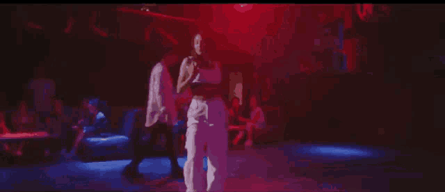 a man and a woman are dancing in front of a crowd in a dark room .