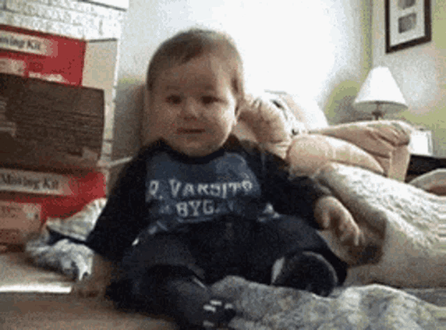 a baby is wearing a varsity byga shirt