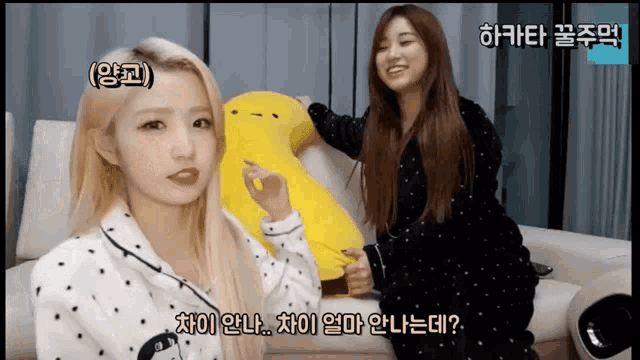 two girls are sitting on a couch and one is holding a stuffed animal