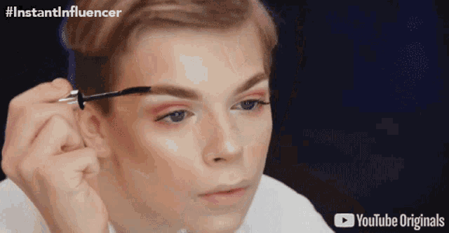 a person is applying mascara to another person 's eyebrows with a youtube originals logo in the corner