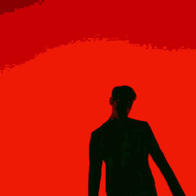 a silhouette of a man in front of a red wall