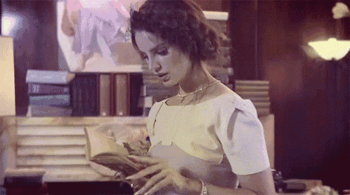 a woman is reading a book in a room with lots of books .