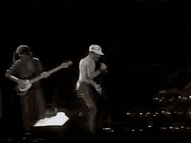 a man is singing into a microphone while a man plays a guitar on stage .