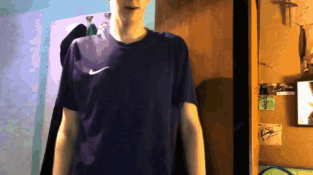 a man wearing a purple nike shirt is standing in a room