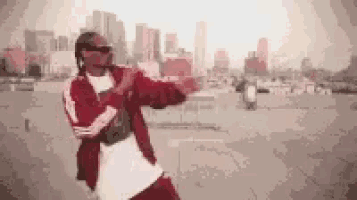 a man in a red jacket is dancing in front of a city skyline .