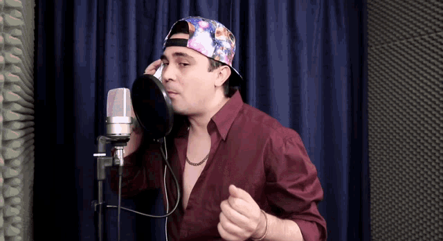 a man singing into a microphone wearing a hat