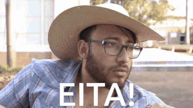 a man wearing a cowboy hat and glasses has the word eita on his chest