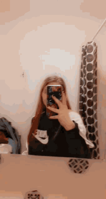 a girl is taking a selfie with her phone in front of a mirror .
