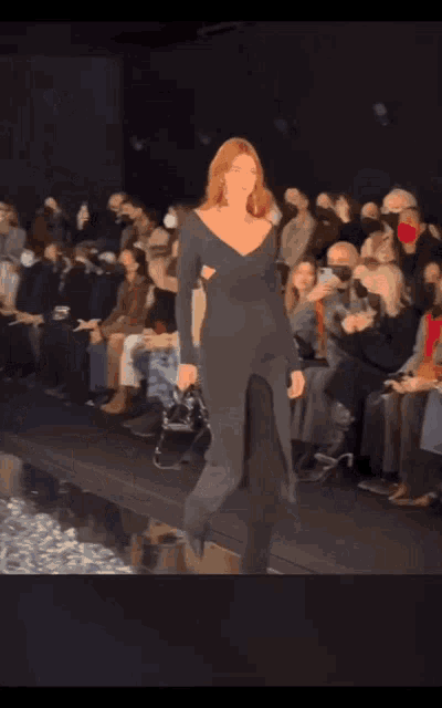 a model walks down the runway at a fashion show with a purse