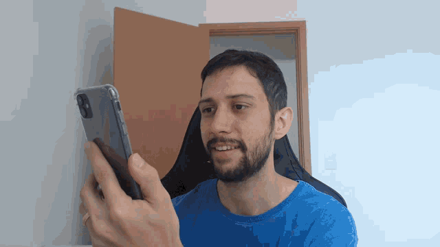 a man in a blue shirt holds a cell phone in his hand