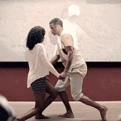 a man and a woman are dancing in front of a screen .