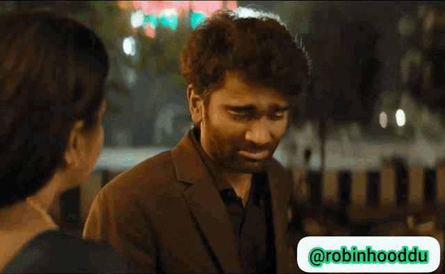 a man in a suit is talking to a woman with a robinhooddu logo in the lower right corner