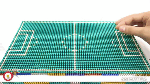 a person is touching a soccer field made of magnetic balls