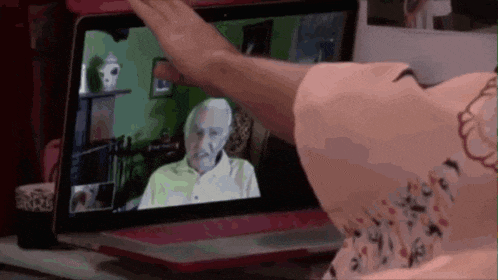 a woman is waving at an older man on a computer screen