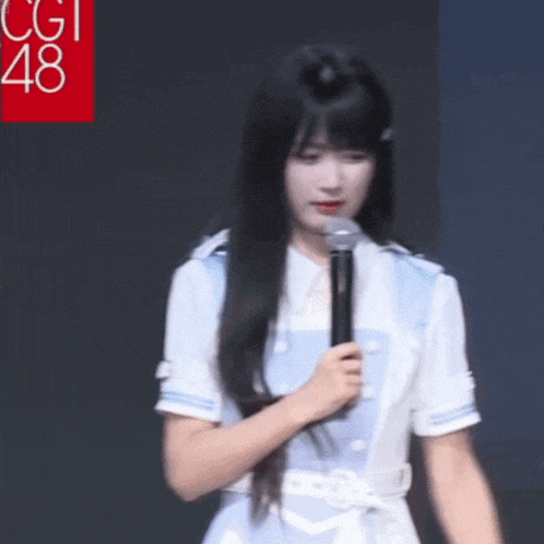 a girl is holding a microphone in front of a sign that says cgi48