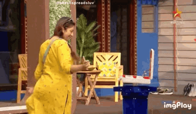 a woman in a yellow dress is standing in front of a blue cooler .