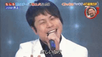 a man in a white jacket is singing into a microphone with chinese writing on it