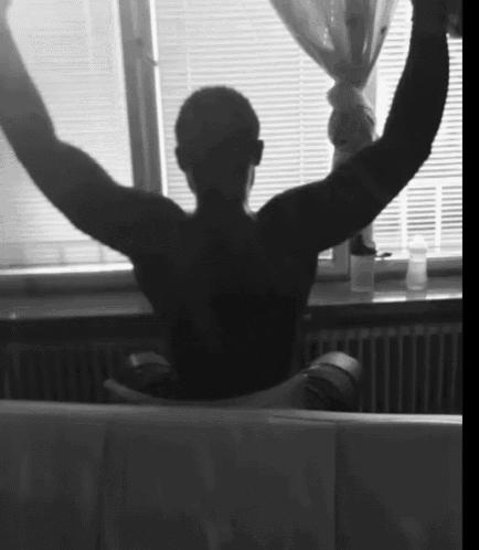 a black and white photo of a man sitting in front of a window