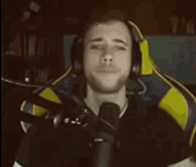 a man wearing headphones and a microphone is singing into a microphone .