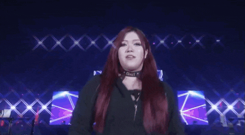 a woman with long red hair is making a funny face while standing on a stage .
