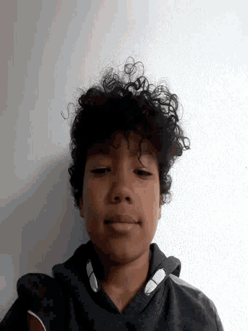 a young boy with curly hair is smiling and looking at the camera