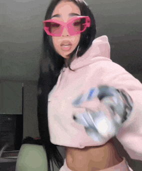 a woman wearing a pink hoodie and pink sunglasses is holding a purse .