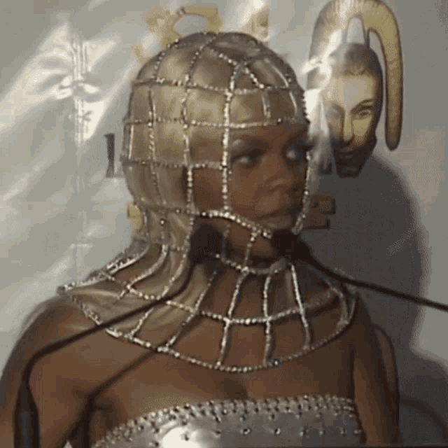 a woman wearing a helmet with rhinestones stands in front of two microphones