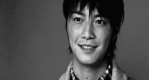 a black and white photo of a young man smiling in a black and white photo .