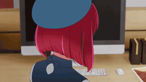 a girl with red hair wearing a blue hat is sitting in front of a computer