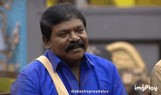 a man with a mustache is wearing a blue shirt and a yellow strap around his shoulder