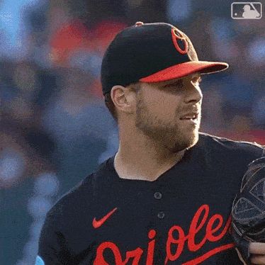 a baseball player wearing an orioles jersey looks to his left