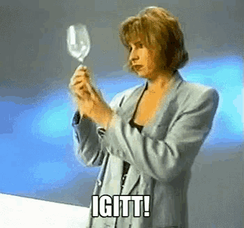 a woman in a suit is holding a wine glass and says " igtt "