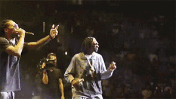 two men are dancing on a stage in front of a crowd of people .