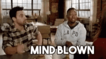 two men are sitting at a table talking to each other and the words mind blown are visible .