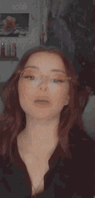 a woman wearing glasses and a black shirt looks at the camera