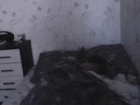 a man is laying on a bed in a dark room with a nightstand .