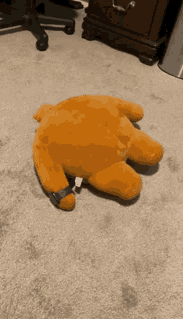 a stuffed animal is laying on the floor with a black strap around its neck