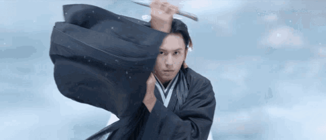 a man in a black robe is holding a sword in his right hand