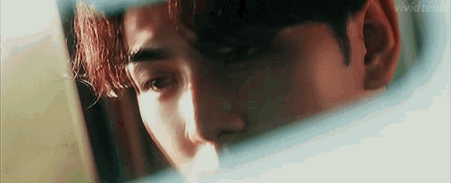 a close up of a man 's face looking out a window
