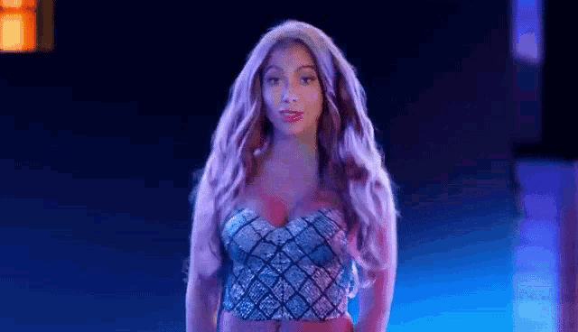 a woman with long blonde hair is standing in front of a blue light in a dark room .