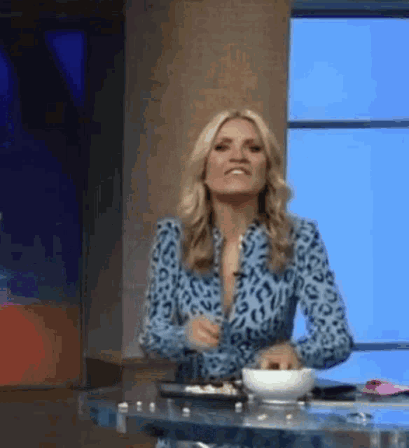 a woman in a blue leopard print shirt is sitting at a table .