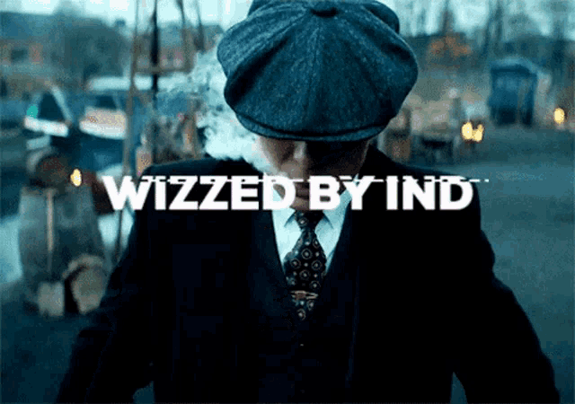 a man in a suit and hat stands in front of a sign that says ' wizzed by ind '