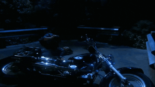 a man laying on the ground next to a black motorcycle