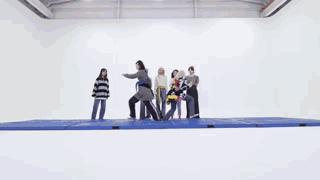 a group of people are standing in a room with a white wall